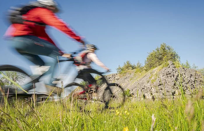 Zwei Fahrradfahrer die Fahrrad fahren und im Hintergrund ist ein kleiner Berg zu sehen
